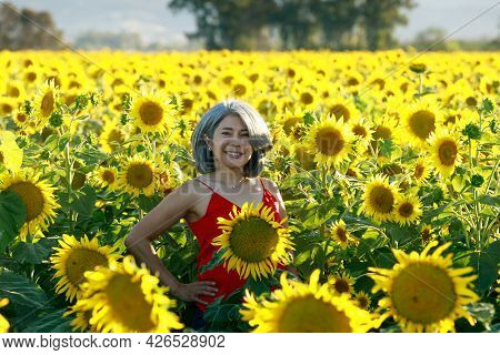 Woman In Red Dress Standing In A Field Of Sunflowers In Summer Bloom. Dixon, Solano County, Californ