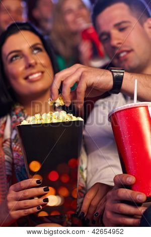 Mladý pár v multiplex kino, jíst popcorn. Zaměřit se na rukou a popcorn.