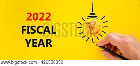 2022 Fiscal New Year Symbol. Businessman Writing Words '2022 Fiscal Year', Isolated On Beautiful Yel
