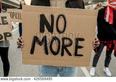 Close-up of unrecognizable person holding benner with No More words while participating in riot