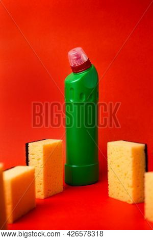 Green Bottle With Cleaning Agent And Cleaning Sponges On A Red Background