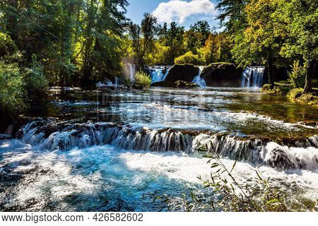Dense forests surround the city and the river. The small Croatian town of Slunj. Magnificent cascade of waterfalls on the Korana River. The concept of ecological, active and photo tourism