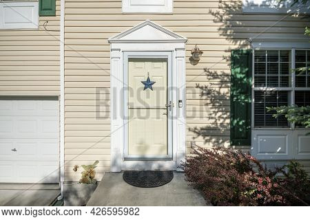 Exterior Of A Front Door With Blue Star, Doorbell, Vinyl Siding Walls And Windows