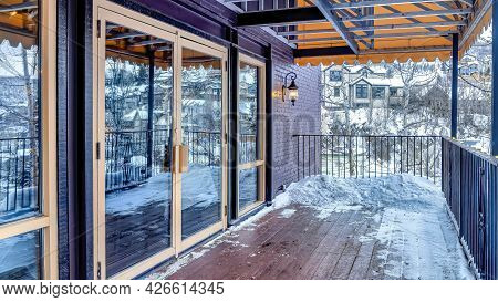 Pano Front Deck Of Building With Double Glass Door And Snow On The Wooden Floor