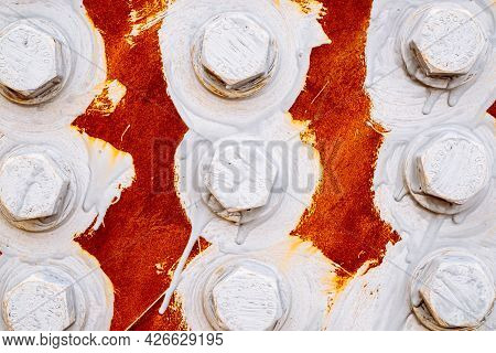 Abstract Background Of Bolts And Nuts Painted White On A Red Background