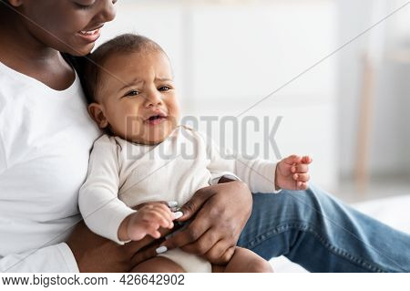 Black Lady Holding Crying Baby With Colic On Hands