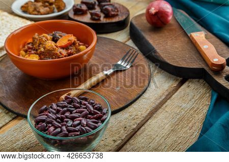 Jewish Dish Chelnt With Meat In A Plate On A Wooden Table On A Stand Next To Ingredients. Horizontal