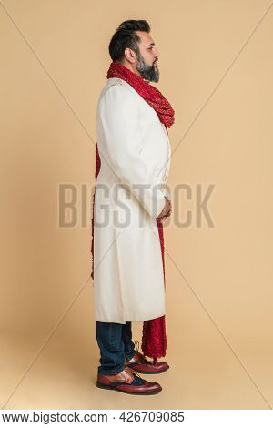 Indian man wearing a kurta with a red scarf in a profile shot