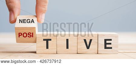 Business Man Hand Holding Wooden Cube With Flip Block Negative To Positive Word On Table Background.