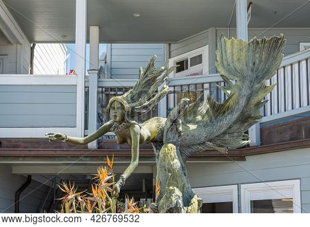 Cayucos, Ca, Usa - June 10, 2021: Floating Naked Mermaid Bronze Statue On Pier View Plaza With Build