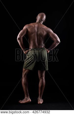 Back View Of A Muscular Man Standing With His Hands On His Waist