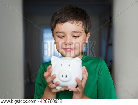 Happy Boy Holding Piggy Bank With Smiling Face. Close Up Portrait Of A Cheerful Child Showing Money 