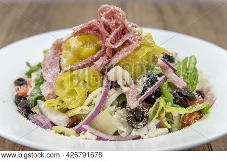 Huge Bowl Of Antipasta Salad With All Fresh Vegetables Chopped And Piled High And Covered In Cheese.