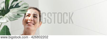 Cheerful woman with a split leaf philodendron