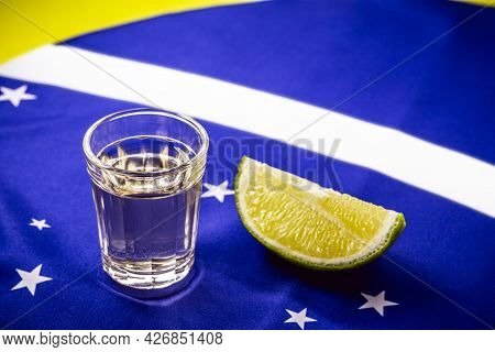 Glass Of Distilled Beverage Made From Sugar Cane, Over The Brazilian Flag, Concept Of The National P