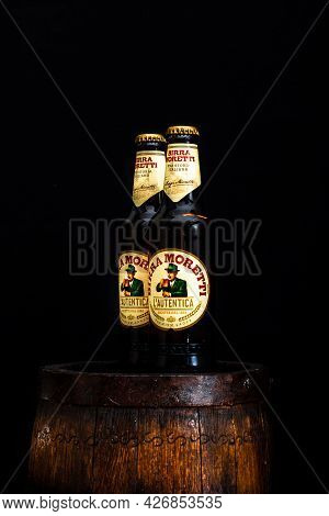 Bottle Of Birra Moretti Beer On Wooden Barrel With Dark Background. Illustrative Editorial Photo Buc
