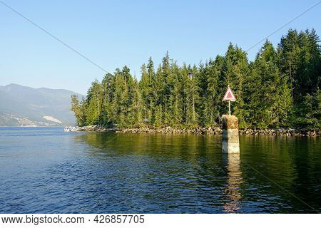 A Low Tide View Of A Starboard Hand Day Beacon, Which Has A Red Triangle Centred On A White Backgrou