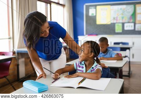 African american female teacher teaching african american girl in the class at elementary school. school and education concept