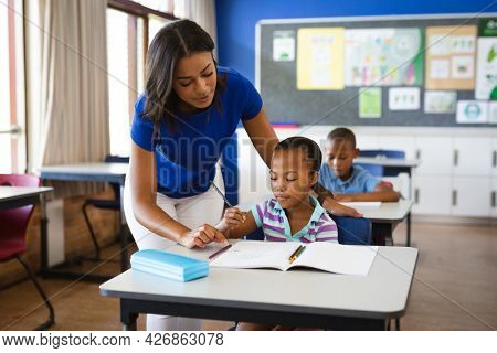 African american female teacher teaching african american girl in the class at elementary school. school and education concept