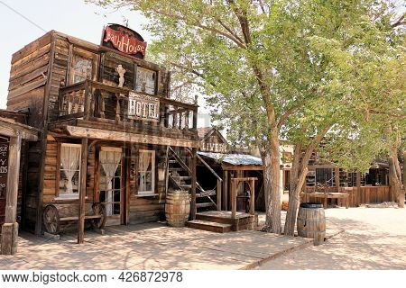 July 14, 2021 In Pioneertown, Ca:  Vintage Rustic Buildings Besides A Wooden Boardwalk And Cottonwoo