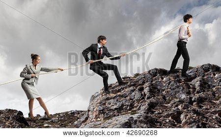 Imagem de três empresários puxando a corda no topo da montanha