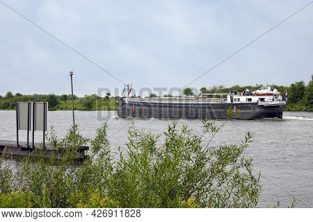 Arcen, The Netherlands - June 24, 2021: Cargo Ship Sailing At Dutch River Meuse Near Village Arcen