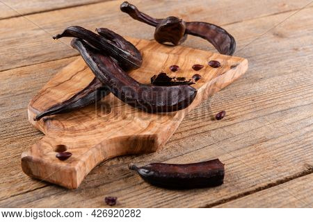 Dry Raw Carob Pods On Wooden Background