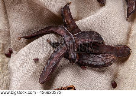 Dry Raw Carob Pods On Wooden Background