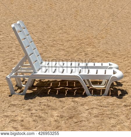 Two White Sun Loungers On The Yellow Sand Under The Sun