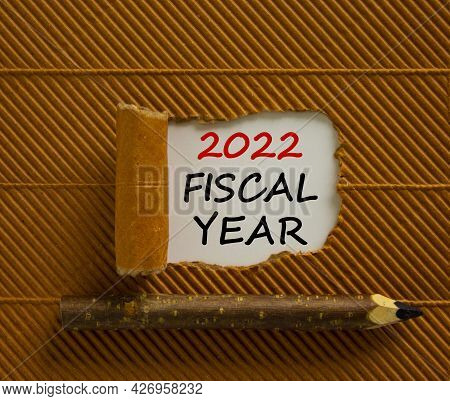 2022 Fiscal New Year Symbol. Words '2022 Fiscal Year' Appearing Behind Torn Brown Paper. Wooden Penc