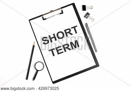 On A White Background Magnifier, A Pen And A Sheet Of Paper With The Text Short Term. Business
