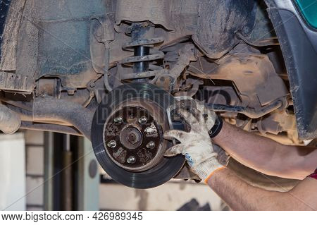 Gloved Male Hands Install Or Remove The Brake Caliper Of An Old Car. In The Garage, A Man Changes Pa