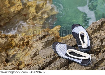 Bathing Shoes On A Stone Coast In The Mediterranean To Protect Against Sea Urchins And Sharp-edged S