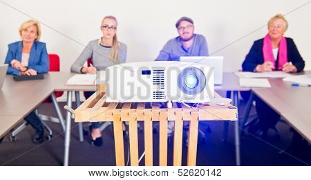 Presentation projector with an audience in a conference room in the background