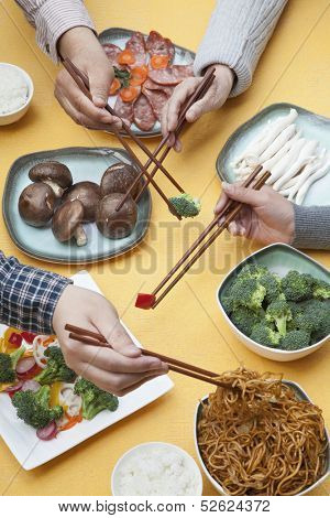 Close up of people using chopsticks with Chinese food