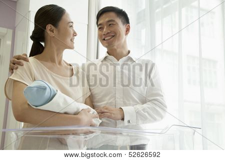Young happy family holding their newborn in the hospital 