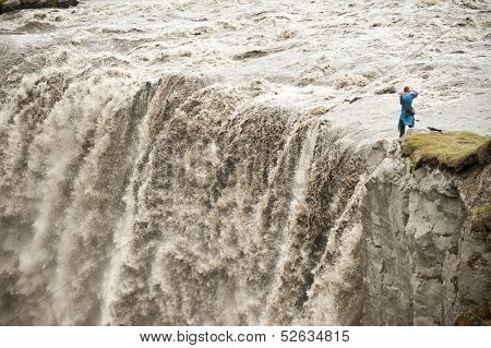 Unrecognizable photographer is taking pictures of Hafragilsfoss, very powerful waterfall. It is located in Jokulsargljufur National Park the northeasten Iceland on the river Jokulsa a Fjollum. 
