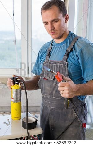 Worker in workwear welds copper tube oxyfuel gas welding