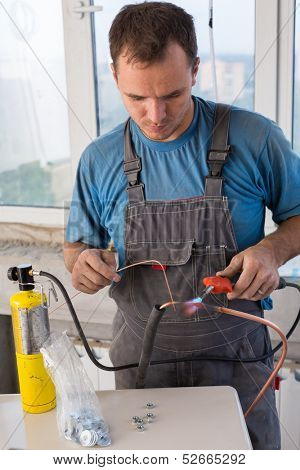 Worker welds copper tube oxyfuel gas welding