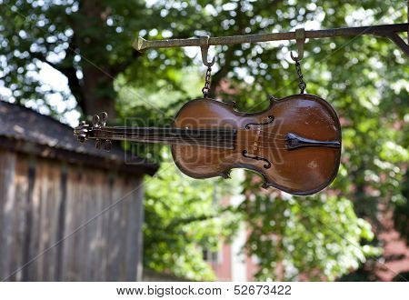 Wooden violin, fiddle in close up hangs above a street.
