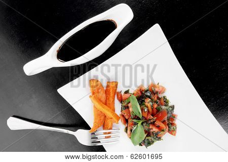 vegetable salad : cherry tomatoes and basil with sweet baked potato served on white plate with sauce boat full blask soy sauce on wood