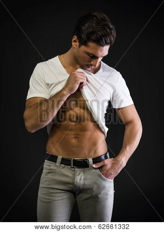 Young Man With Muscular Body Pulling Up T-shirt