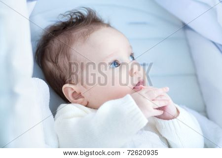 Beautiful Little Baby Relaxing In A Stroller Wearing A Warm Hite Sweater
