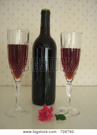 Celebrating.Two kopper af rødvin, flaske vin, og rød Rose