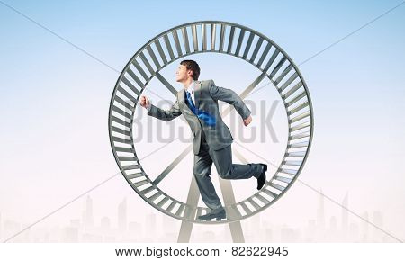 Young businessman running in huge hamster wheel