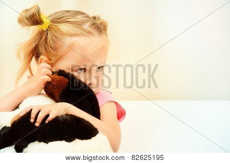 Sad little girl hugging her toy.