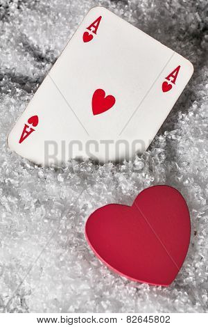Red heart with ace of hearts in the snow