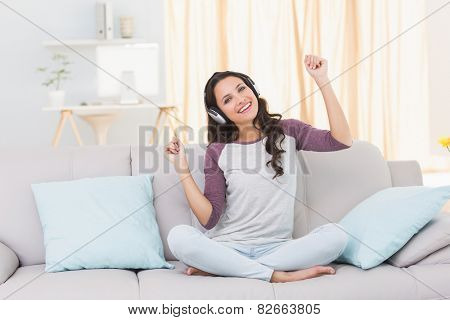 Pretty brunette listening to music on the couch at home in the living room