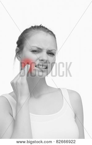 Young woman massaging her jaw against white background
