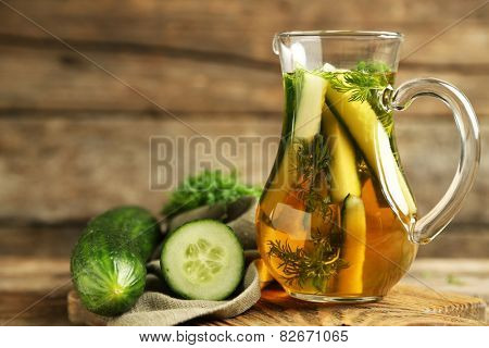 Glass ewer with fresh organic cucumber water on wooden table